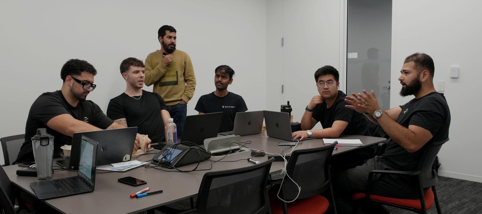 Six of our team in a working session around a boardroom table, laptops open, mid-discussion.