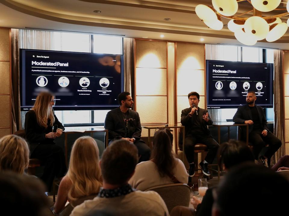 A Zero to Agent panel on stage in a chandelier-lit room, the audience seen from behind.